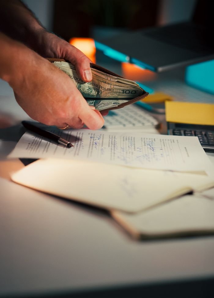 services-06 Person handling cash with documents and pen on a desk, suggesting financial management.