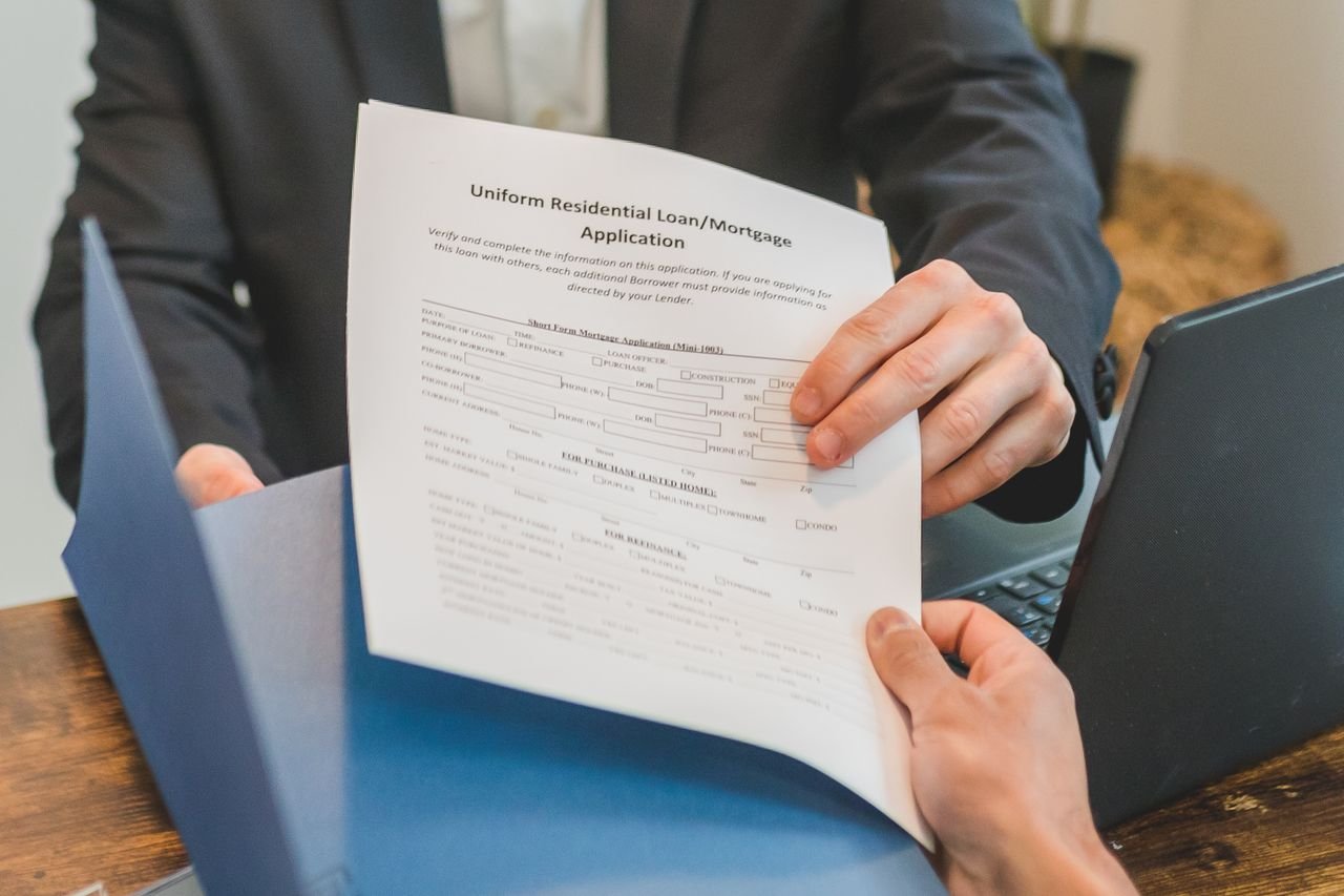 home-hero Professional setting showing hands exchanging a mortgage application document indoors.
